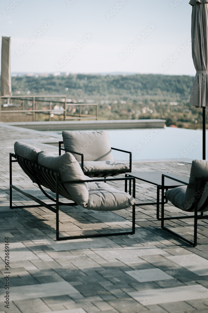 Fototapeta premium Comfortable outdoor seating area overlooking a scenic landscape near a swimming pool