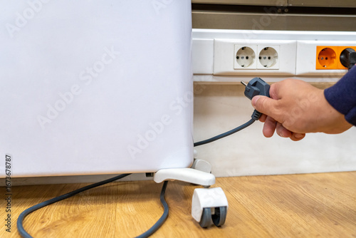 Принти на полотні Close-up of person's hand holding electrical plug, preparing to connect applianc