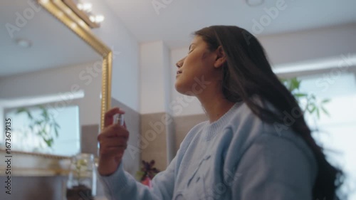Latina Woman Applying Perfume in Bathroom Mirror Before Going Out