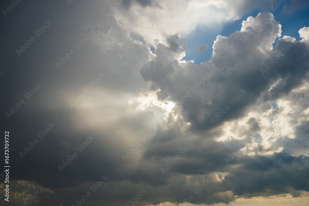 Obraz premium Sunbeams filtering through a dramatic cloudscape create a breathtaking interplay of light and shadow, showcasing the vastness of the sky and evoking a sense of peace and inspiration