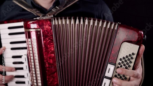 Musician plays vibrant accordion with intricate details in a dimly lit studio