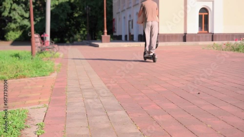 Senior man rides scooter along pathway in park on sunny day