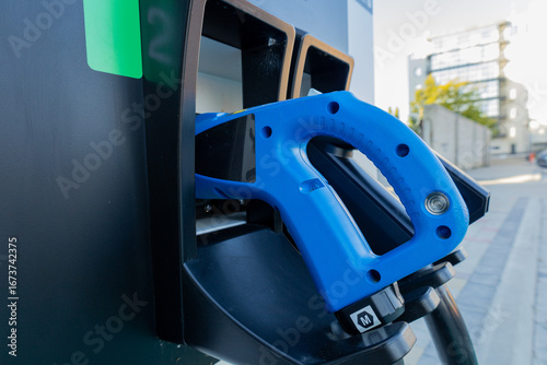 Wallpaper Mural Blue fuel nozzle is positioned at a fueling station in an urban environment, ready for vehicles to fill up during bright daylight hours Torontodigital.ca