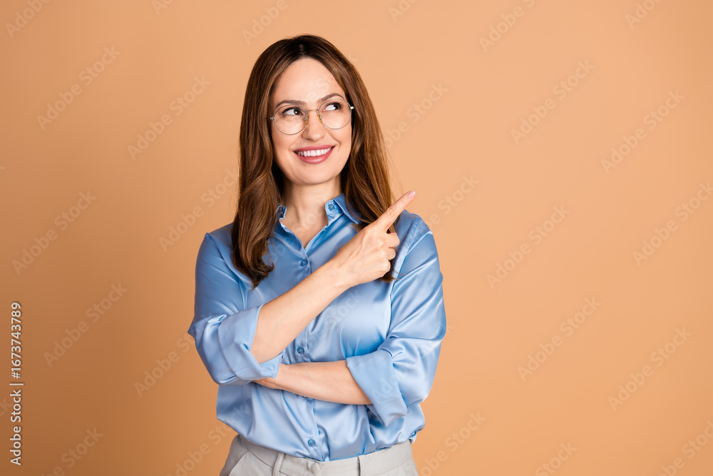 Confident businesswoman in blue blouse gesturing with smile, standing against beige background embracing her success Confident businesswoman in blue blouse gesturing with smile, standing against beige background embracing her success