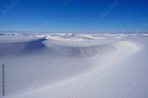 Vast frozen desert landscape under a clear blue sky with rolling snow dunes