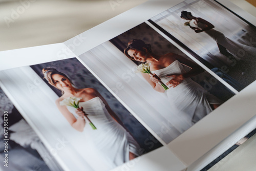 page of an open photo book with wedding photos on a white table