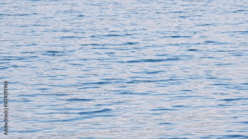 4K static video of ocean waves, caused by the wind, moving over the surface of the liquid and reflecting the clouds in the sky, creating ghostly shapes and revealing the beauty of the liquid element