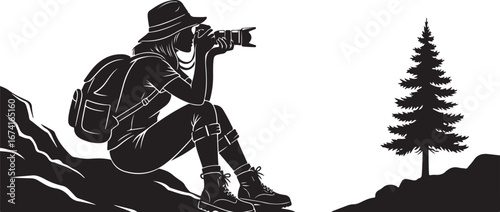 Silhouette of a female hiker with a backpack taking a photo on a rocky cliff with a pine tree