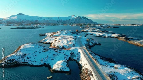 aerial footage showcasing the iconic Atlantic Ocean Road Atlanterhavsveien in Norway, transformed by a blanket of pristine white snow during winter.