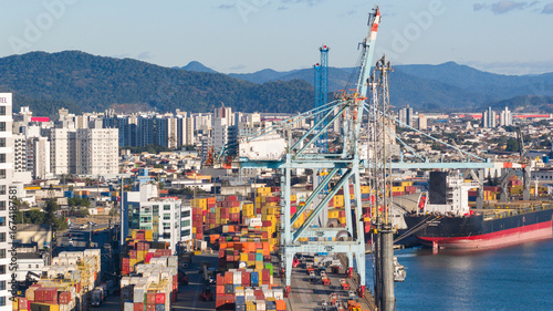 Large crane operating at the Port of Itajaí with shipping containers and cargo vessels in view.