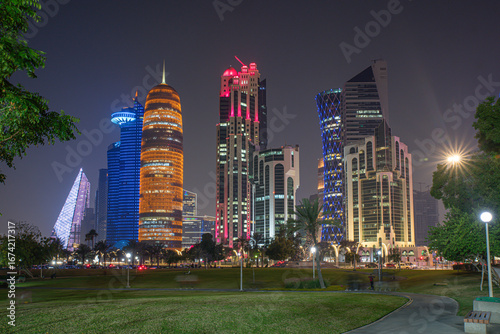Doha city business downtown center panorama illuminated at night, with modern skyscrapers and sea in the foreground, Qatar