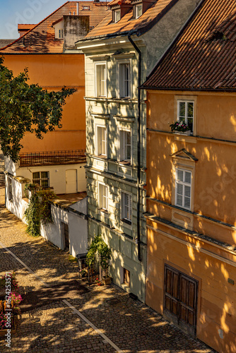 Elegant riverside houses resting in shadow along Prague’s cobblestone streets