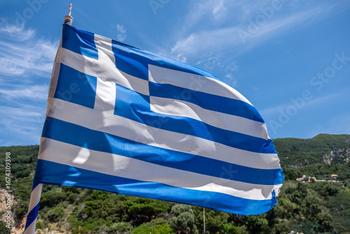 Greece sign symbol. Greek national flag on flagpole waving in the wind, blue sky