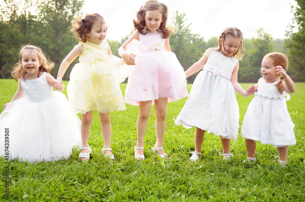 Naklejka premium Five Happy Little Girls Holding Hands and Jumping Together Outside