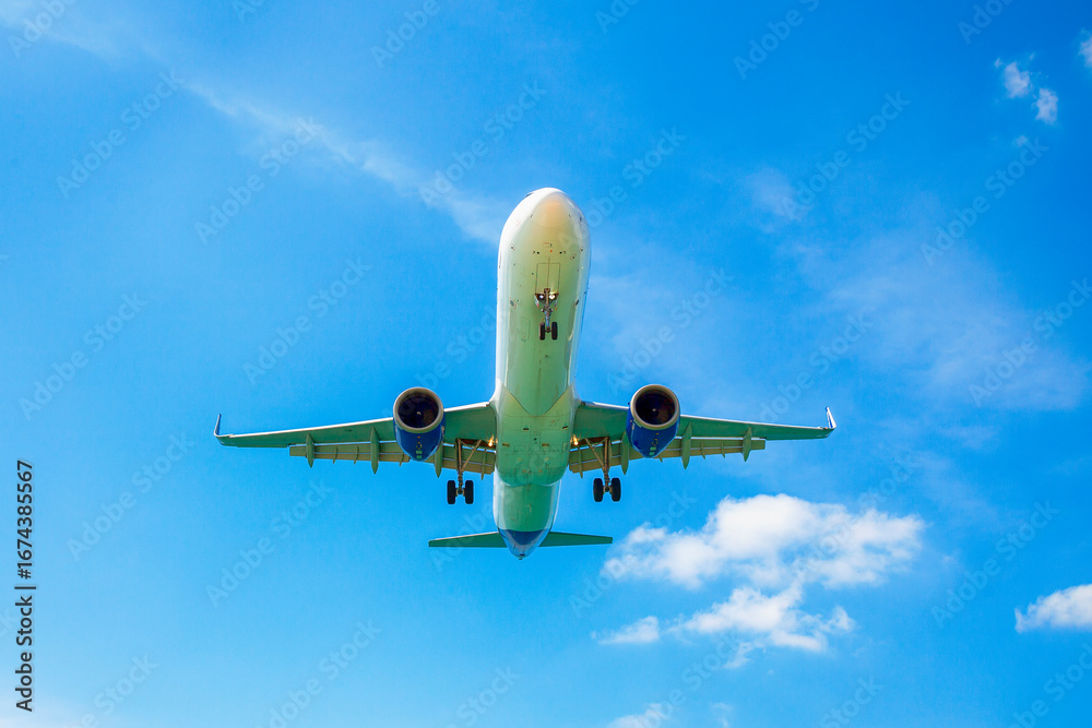 Obraz premium Passenger airplane flying in the sky. Travel background with airplane flying in the blue sky. View directly in front. Passenger plane landing.