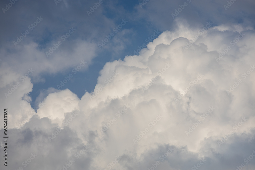 Fototapeta premium Fluffy white clouds drifting against a bright blue sky during a sunny afternoon