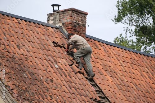 Sihouette of man repairs the roof tiles in background.