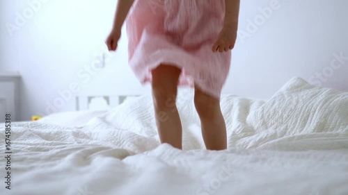 Preschooler girl jumping on the bed at home