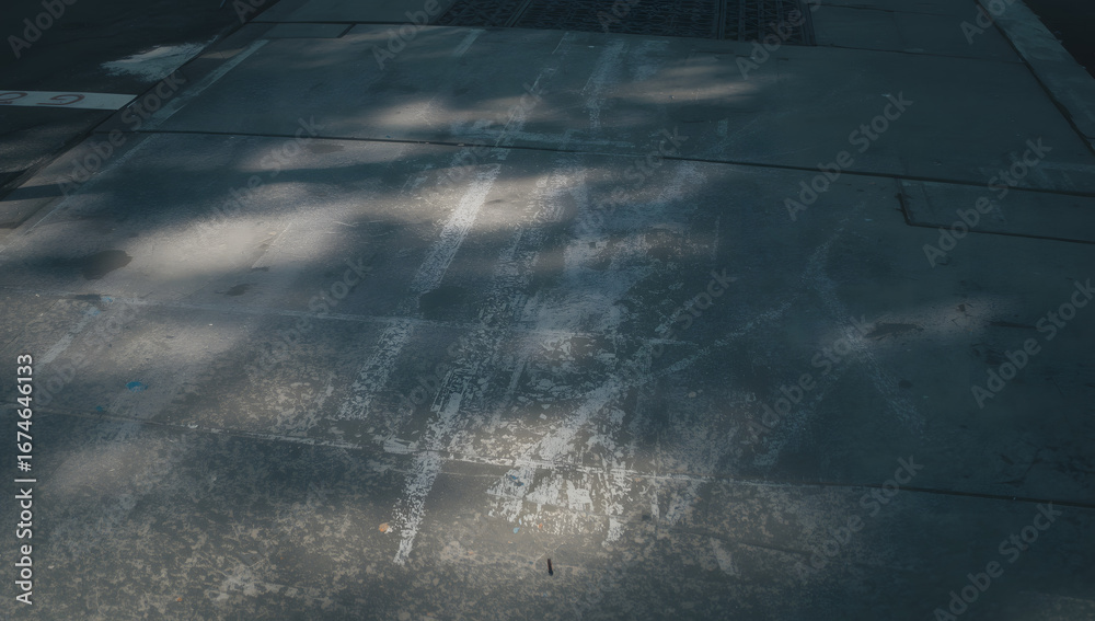 Fototapeta premium Urban sidewalk pavement with shadows and markings.