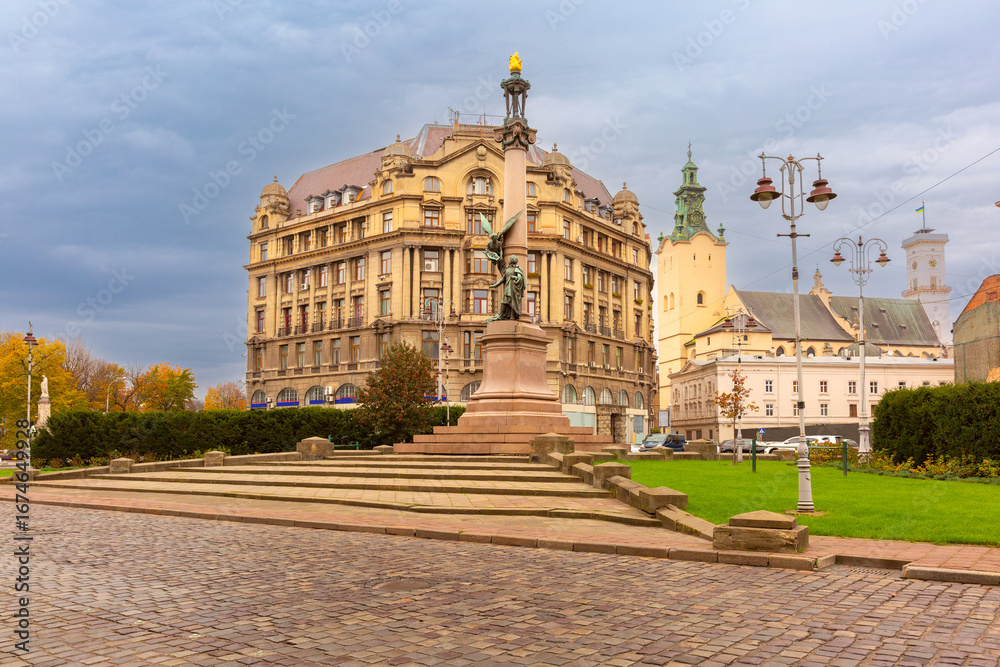 Obraz premium Adam Mickiewicz Monument in Lviv city center, Ukraine, with surrounding historic buildings and churches