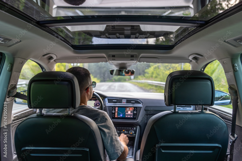 Modern road trip in car with panoramic roof. Driver on summer road Modern road trip in car with panoramic roof. Driver on summer road
