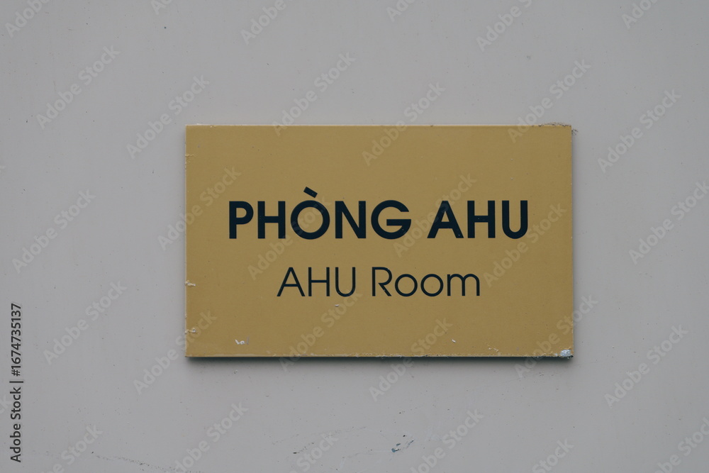 Obraz premium PHÒNG AHU AHU Room sign. Bilingual text in Vietnamese and English on a yellow plaque mounted on a gray wall, indicating an Air Handling Unit room.