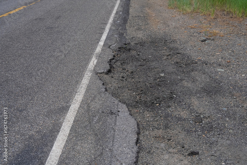 Large pothole disrupts a paved road, highlighting the need for maintenance and repair.