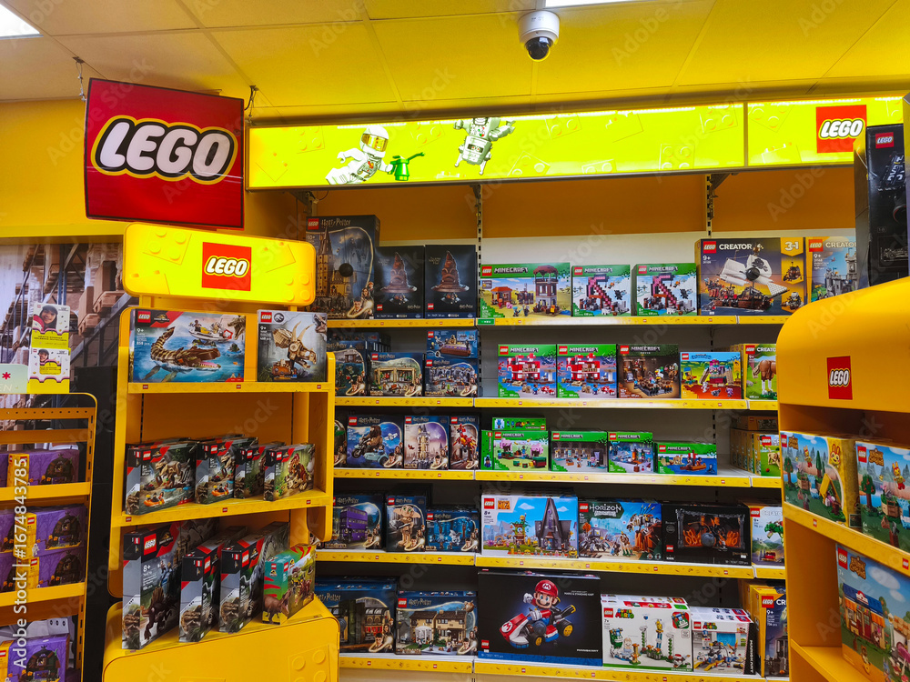 Naklejka premium Potsdam, Germany - August 30, 2025: LEGO toy store display featuring colorful building sets on shelves, showcasing various themes and characters in a vibrant retail environment