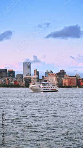 Modern cruise boat slowly moves by the East River. City skyline at backdrop. New York boat tour. Vertical video.