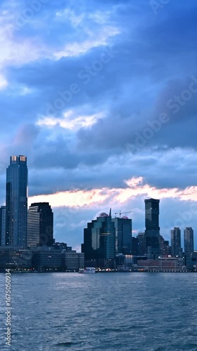 Grey dramatic clouds gathered above the skyline of New York. View on metropolis from the riverscape at dusk time. Vertical video.