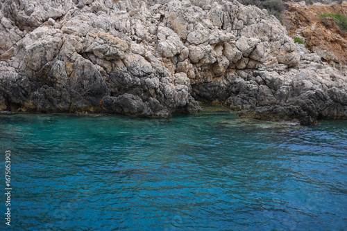 Rocky land in the mediterranean sea on sunny day and blue sky. Turquoise water and bright summer atmosphere