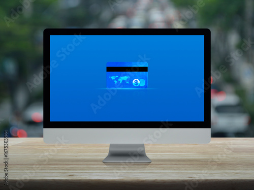 Fototapeta Naklejka Na Ścianę i Meble -  Credit card on modern computer monitor screen on wooden table over blur of rush hour with cars and road in city, Online e-payment concept, Elements of this image furnished by NASA