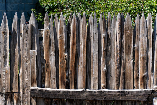 A stockade is a fence made of wooden stakes driven closely into the ground, pointed at the top. An old wooden palisade darkened with age.