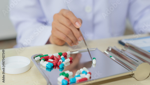 Tableau sur toile Pharmacist sorting colorful capsule medication on metal tray in pharmacy, health