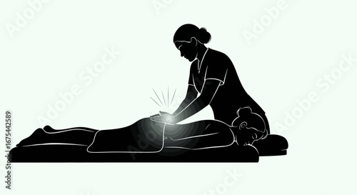 Silhouette of a massage therapist giving a treatment to a client on a massage table with a glowing spot