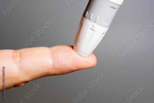 Картината върху платно A close-up of a lancet device poised to prick a person's fingertip for a blood sample