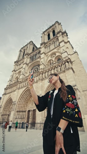 Tourist taking a selfie against the backdrop of Notre Dame de Paris. Beautiful walks in the tourist capital of France, historical architecture.