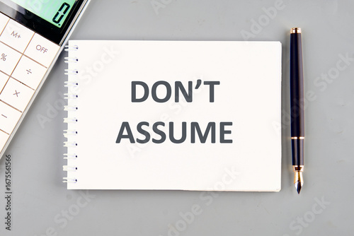 The words Don't Assume in a notebook on a gray background