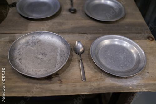 Aluminum bowl with a spoon on the background of wood. An old aluminum plate on wooden boards.
