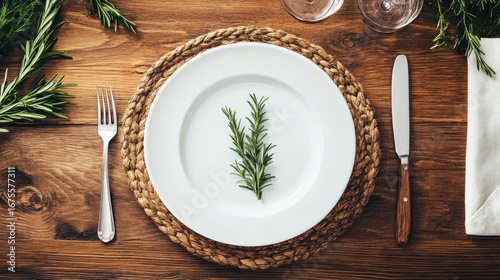 Elegant, rustic table setting with fresh rosemary sprigs on a white plate.
