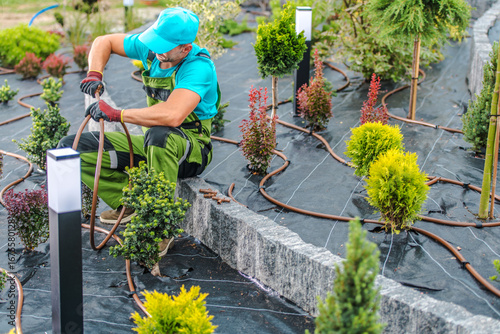 Gardener Installing Irrigation System in Landscaped Garden During Daytime