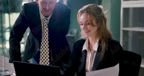 Confident businesswoman smiling while reviewing document with male colleague. Team members analyzing report in corporate meeting for business planning in professional workspace