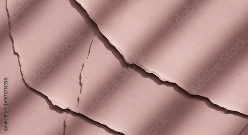 Close-up of a cracked, light pink surface with diagonal shadows creating a textured, abstract composition.