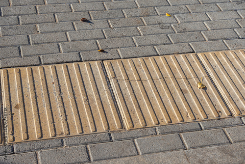 Paving slabs made of cement mix. A crack in the road tile. Tactile coating for the visually impaired. Tactile tiles that help visually impaired pedestrians navigate. Tactile warnings.