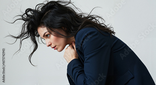 Woman in navy suit with wild hair showing thoughtful expression  