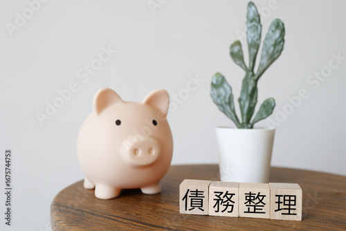 債務整理と貯金のイメージ、ブタの貯金箱と観葉植物。