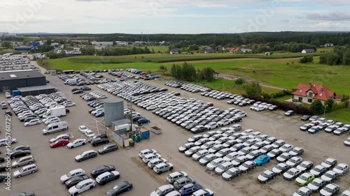 Large car storage lot with rows of parked vehicles near dealership