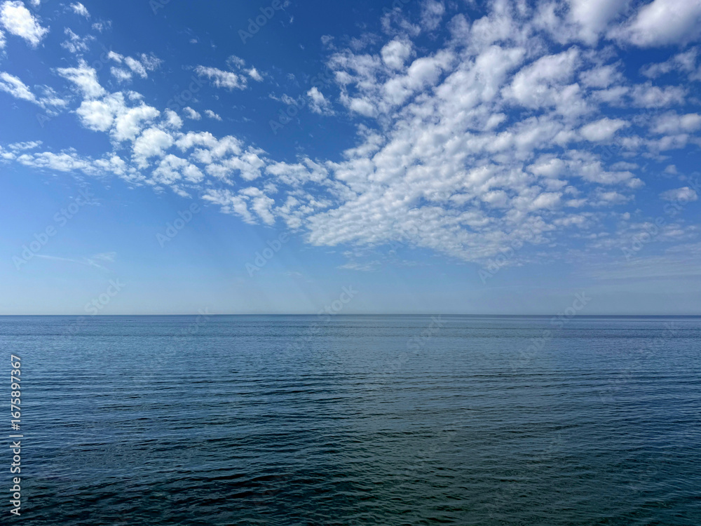 Fototapeta premium Blue sky with clouds and blue calm sea.