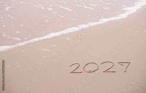 2027 year handwritten on the beach in the sunset time. New Year 2027 concept