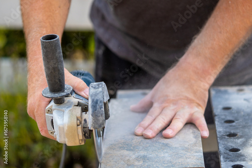 Mann schleift mit einem Winkelschleifer eine Fliese